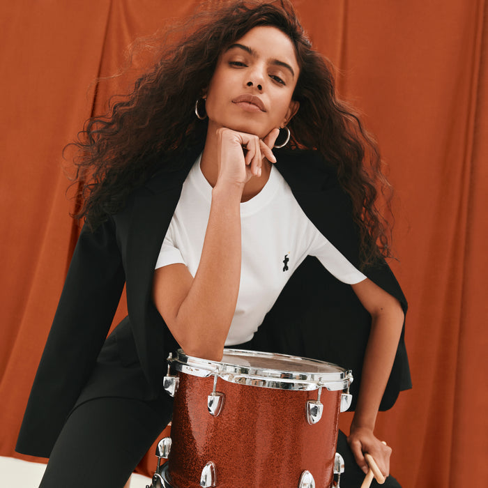 image of a woman sitting with a drum wearing the leslie tshirt in embroidered pima cotton
