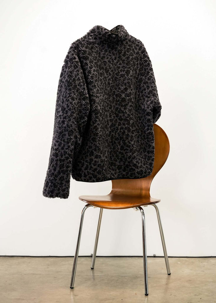 Stylish Black Leopard Fleece Jacket displayed on a chair, showcasing its modern design and luxurious texture.