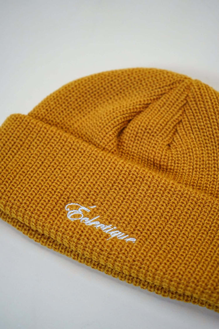 Mustard fisherman beanie with white logo embroidery by Éclectique, 58cm circumference, made from 70% recycled polyester.