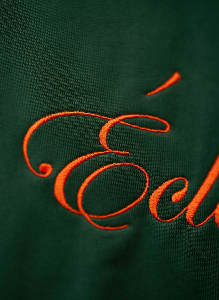Close-up of the embroidered Éclectique script logo on the emerald script logo embroidered cotton t-shirt.