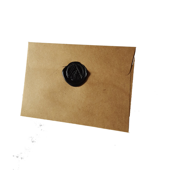 A brown envelope from At My Mercy, sealed with black wax featuring a triangle and lines, set against a white background.