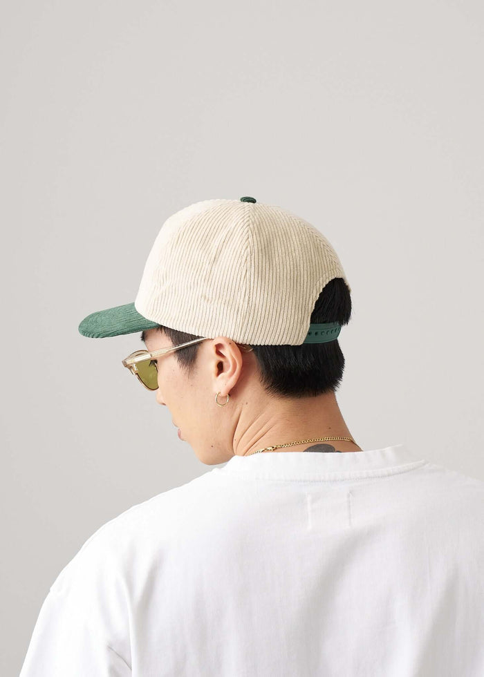 Back view of a person wearing a Two Tone Snapback Hat in Green & Natural with sunglasses.