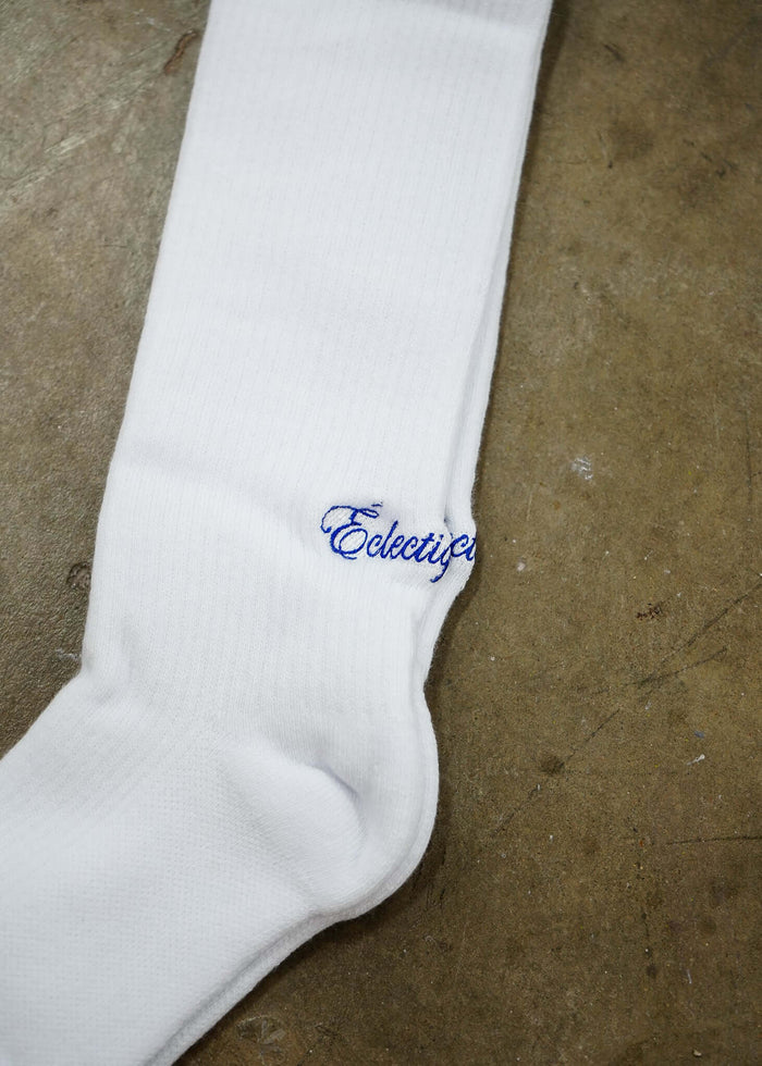 White logo socks featuring Éclectique’s blue script logo on a soft white cotton fabric.