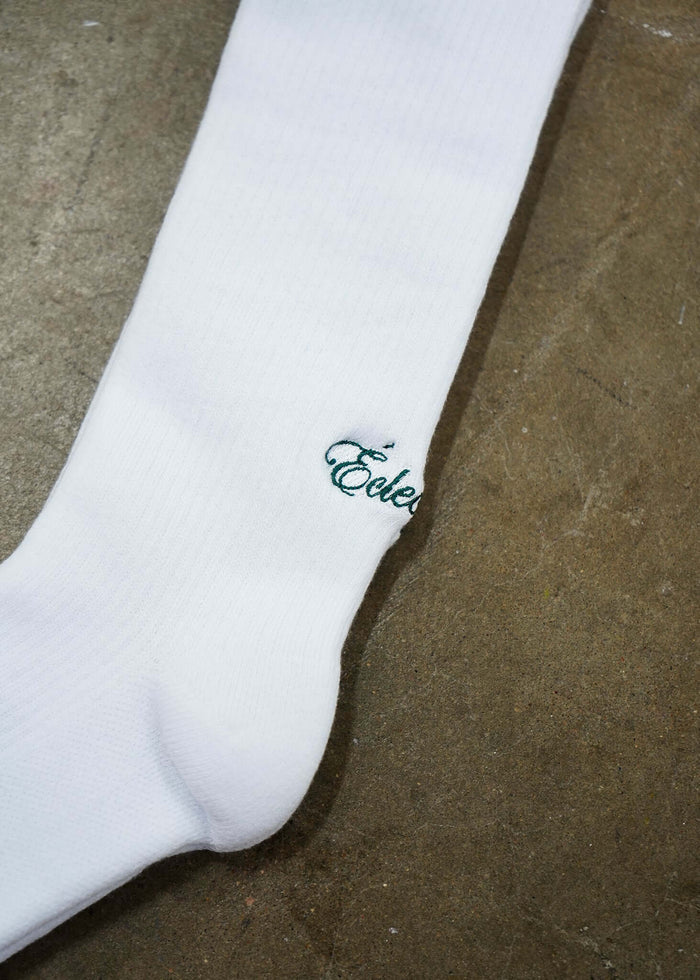 White Logo Socks featuring Éclectique’s green script logo on a white background.