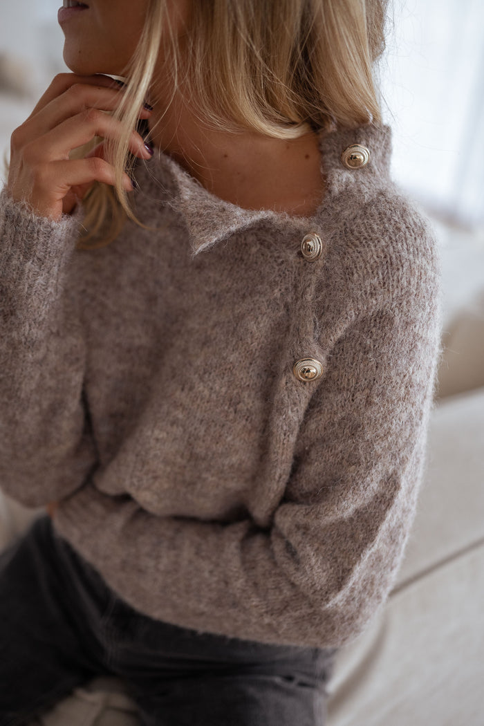 Beige mockneck knit sweater with gold shoulder buttons