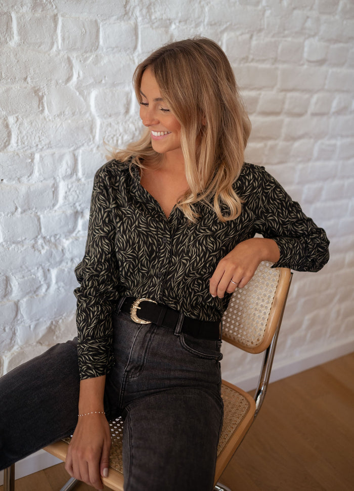 Woman wearing black and green print shirt with jeans