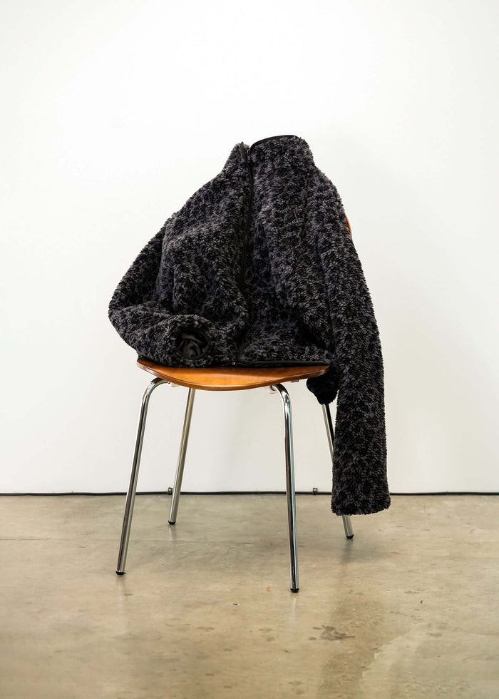 Black Leopard Fleece Jacket draped over a chair showcasing its stylish design and cozy texture.