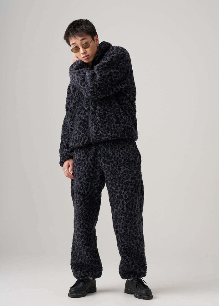 Model wearing black leopard fleece pants and matching jacket, showcasing a chic and comfortable outfit.
