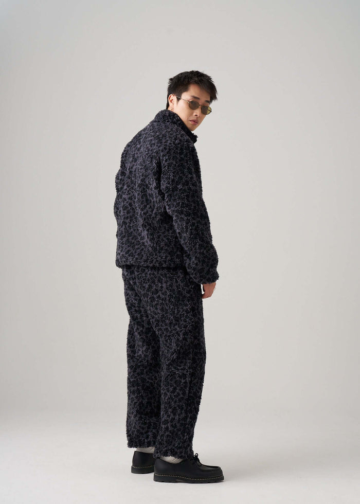 Man wearing black leopard fleece pants and matching jacket, showcasing a stylish and relaxed outfit.