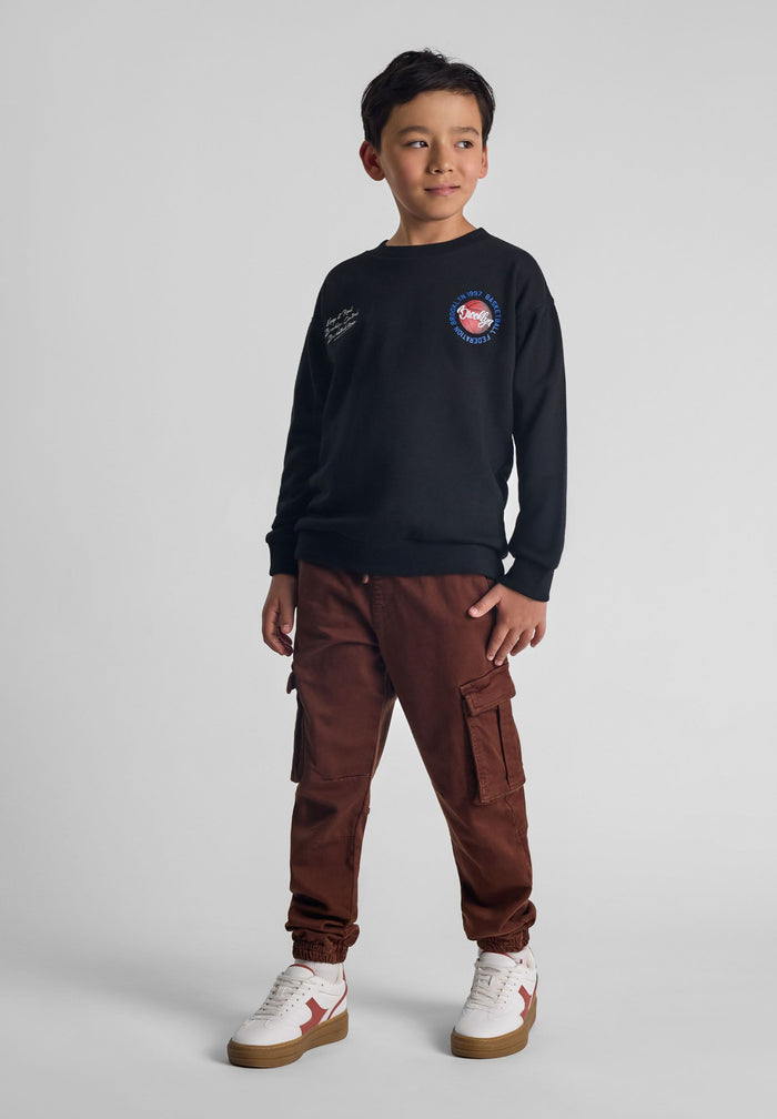 Boys brown cargo trousers, front view, featuring cargo pockets and ribbed ankle cuffs.