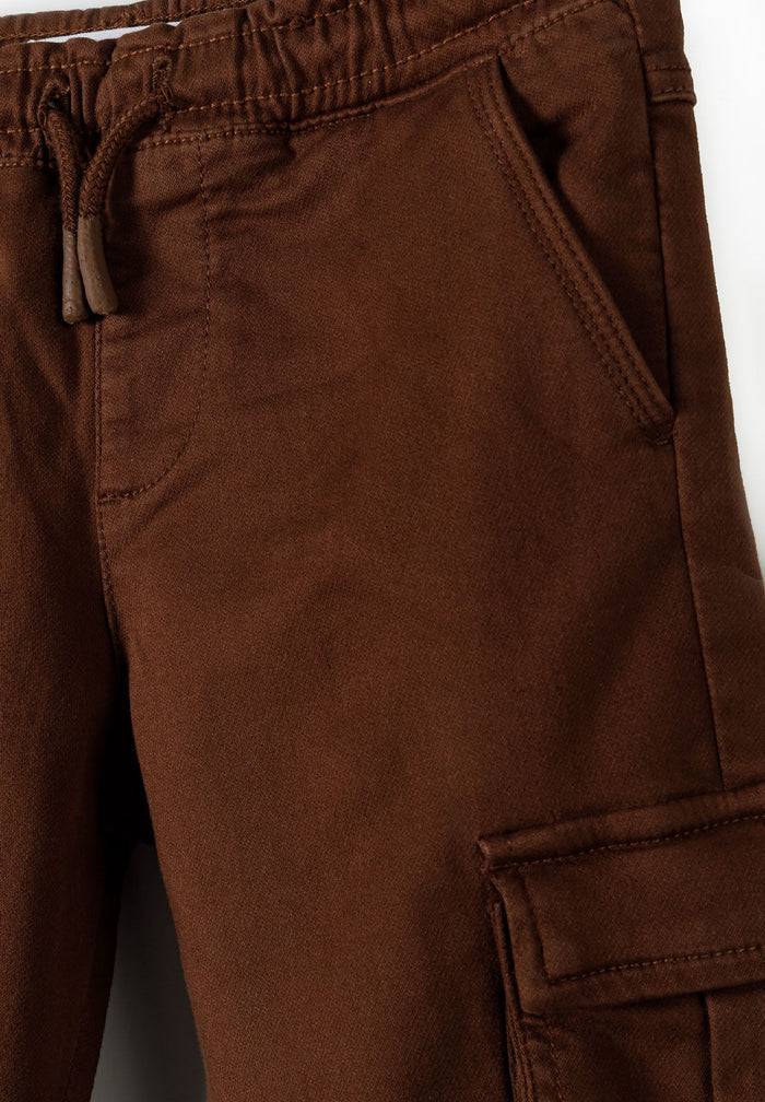 Close-up of brown cargo trousers for boys with elastic waistband and side pockets.