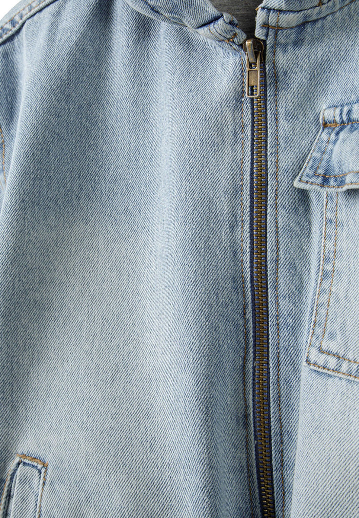 Detail of boys light blue denim jacket with hood and zip fastening.