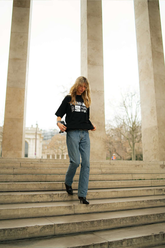 Model wearing Brooklyn graphic t-shirt and jeans, walking down stairs outside, showcasing stylish urban fashion.