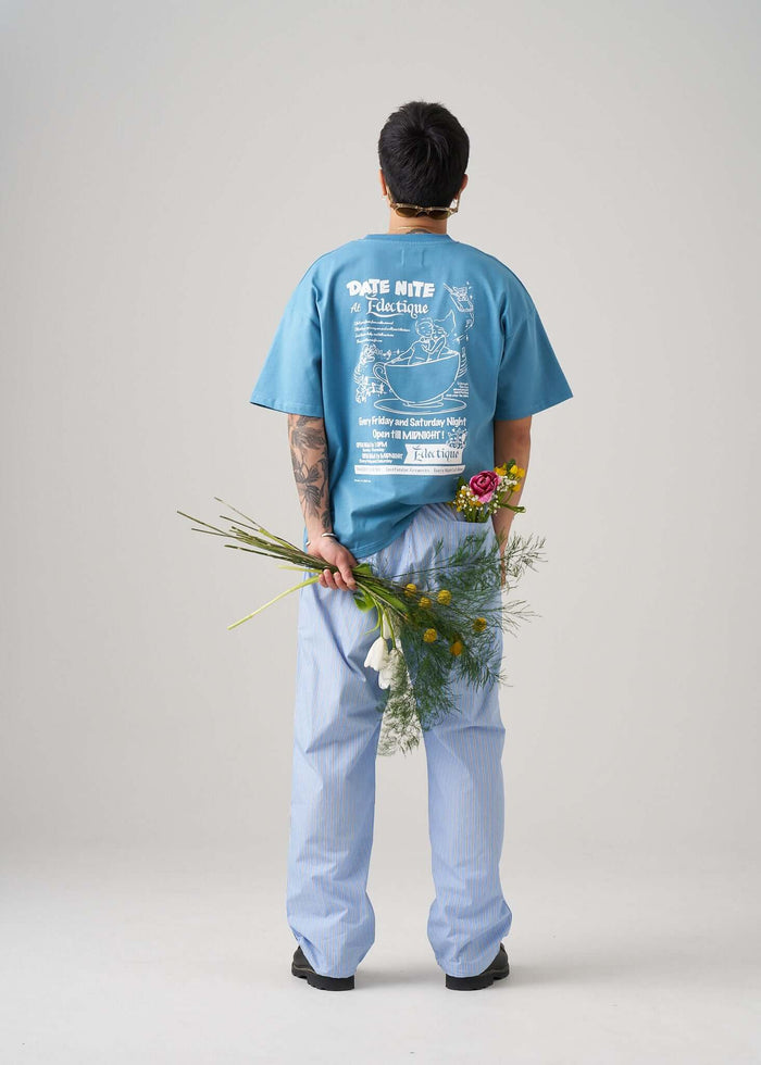 Person holding flowers wearing the Carolina Blue Date Night T-shirt by Éclectique, showcasing its stylish back design.