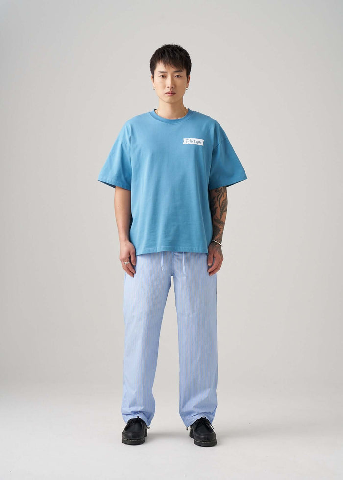Model wearing a Carolina Blue Date Night T-shirt with light striped pants in a studio setting.