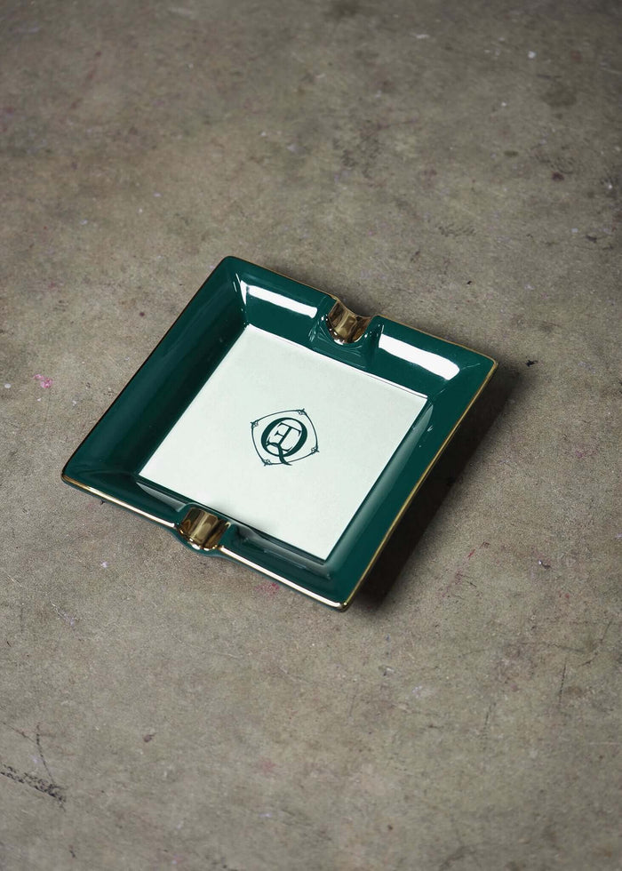 Green ceramic catchall tray with gold trim and monogram logo, ideal for jewelry or as an upscale ashtray.