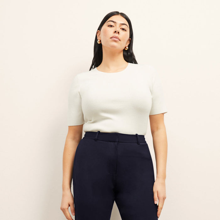 Front image of a woman standing wearing the choe top in ivory