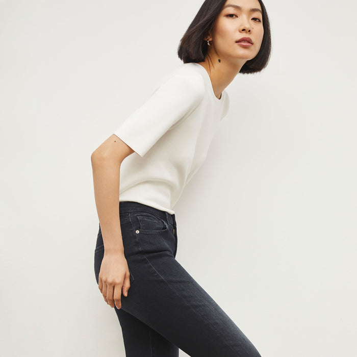 Side image of a woman standing wearing the choe top in ivory