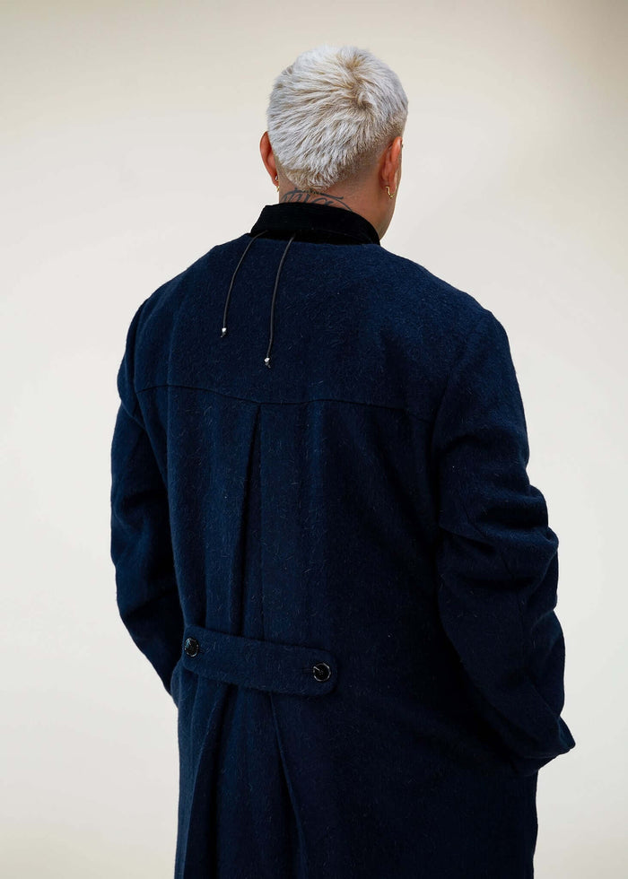 Model wearing Éclectique collarless long coat in navy back view