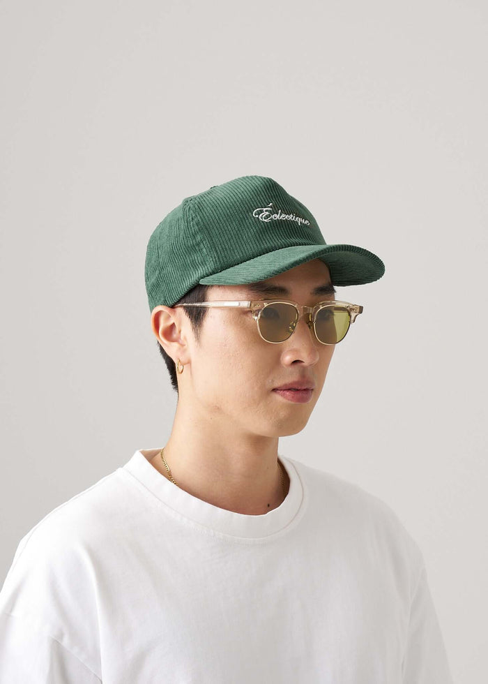 Corduroy script logo snapback hat worn by a young man with sunglasses.