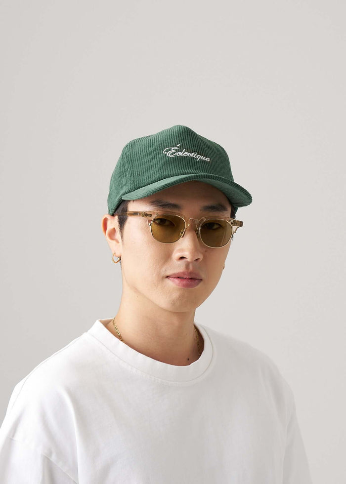 Man wearing a Corduroy script logo snapback hat in June Bug Green with sunglasses.