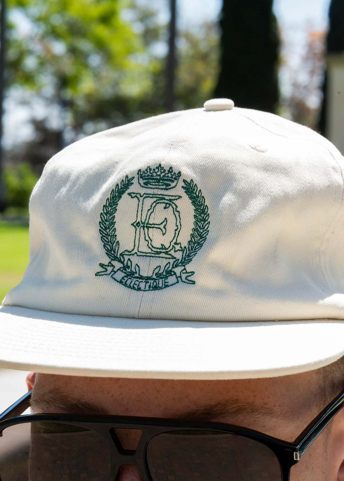 Éclectique Crest embroidered dad hat featuring a refined crest design on a vanilla ice cotton twill base.