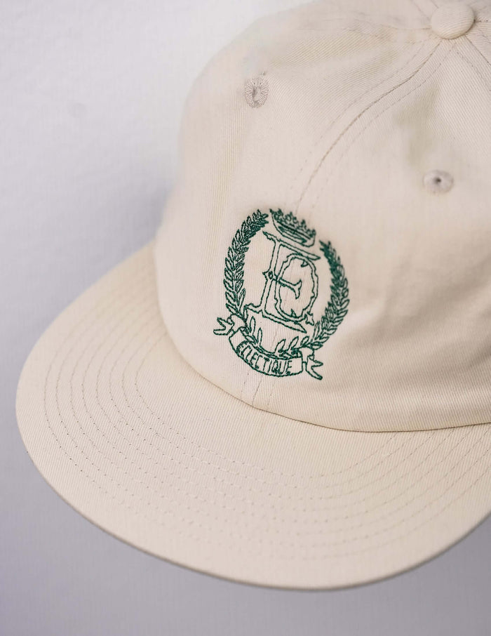 Side view of Éclectique crest embroidered dad hat in off-white cotton