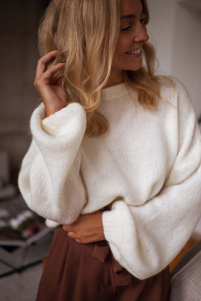 Woman wearing ecru sweater with brown trousers