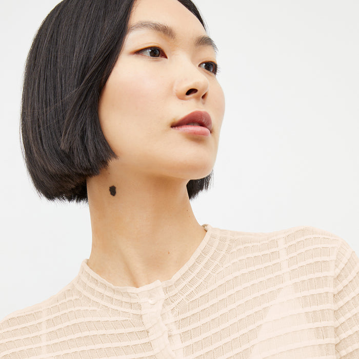 Close image of a woman standing wearing the Emerson Cardigan in Meringue