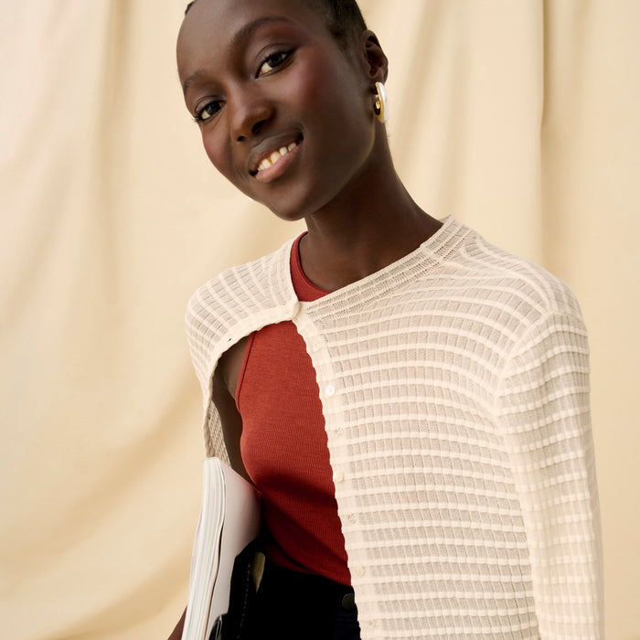Front image of a woman sitting wearing the Emerson Cardigan in Meringue