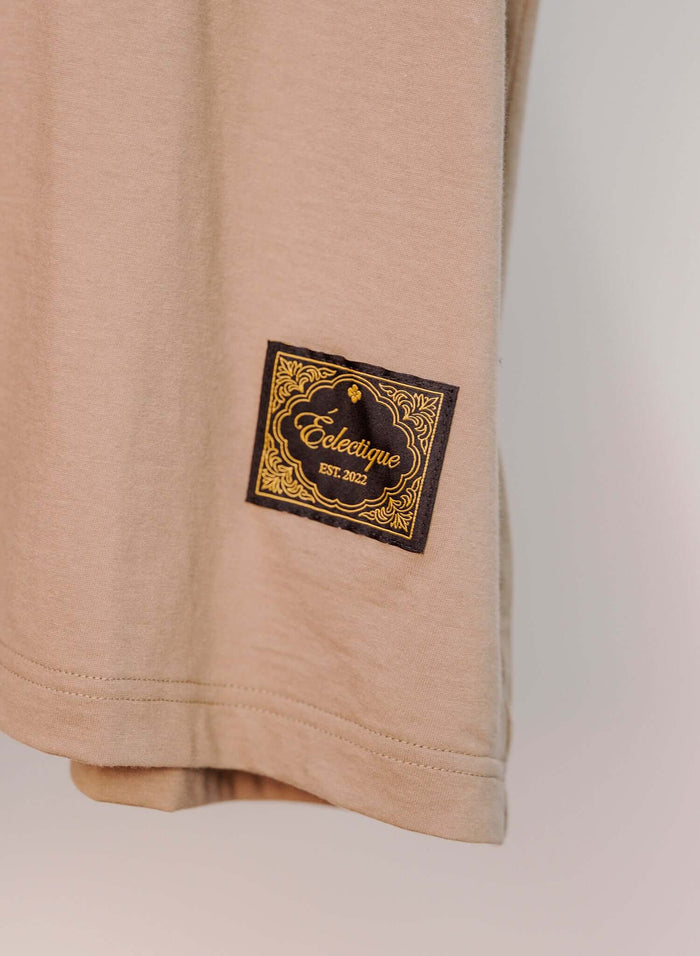 Japanese Made Close-up of Éclectique woven label on the Essential Cotton T-shirt in sand, showcasing quality craftsmanship.