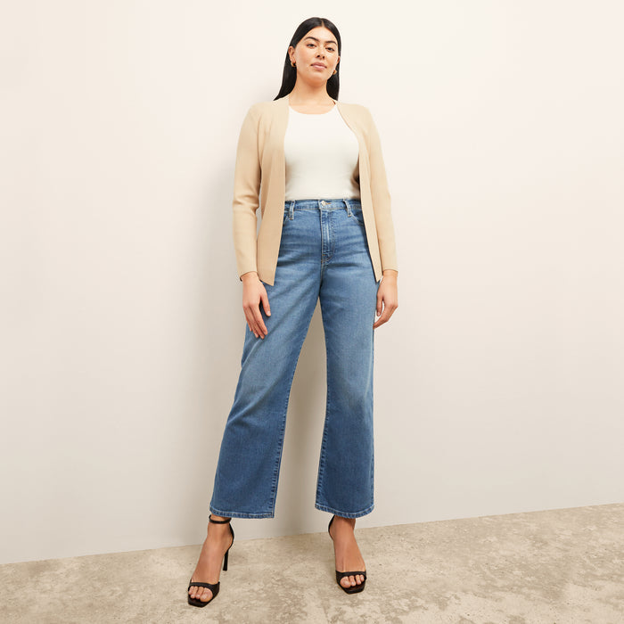 front image of a woman sitting wearing the frame le jane ankle jeans in deepwater