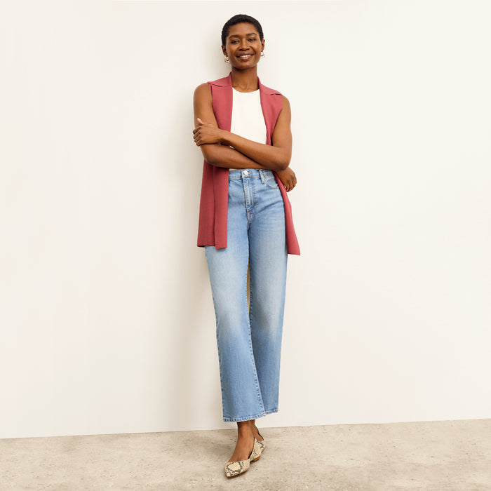 front image of a woman sitting wearing the frame le jane ankle jeans in deepwater
