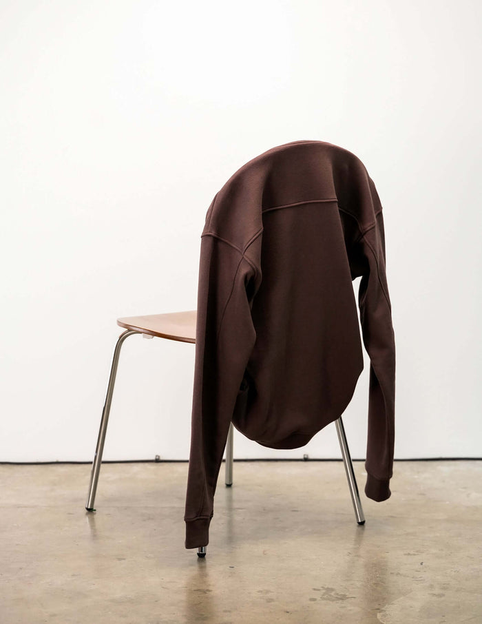 French Terry crewneck sweatshirt hanging on a chair, showcasing its sleek design and comfortable fabric.