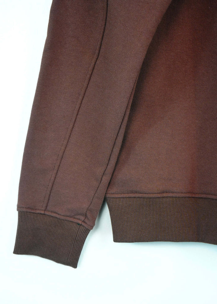Detail of the sleeve and cuff of a French Terry crewneck sweatshirt in rich brown color.