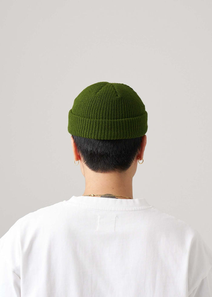 Green fisherman beanie displayed on a model's head, showcasing its stylish design and emerald color.