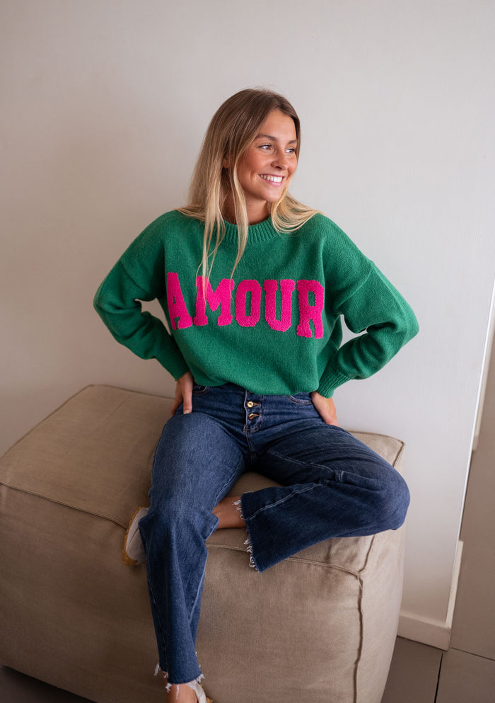 Woman wearing green AMOUR logo sweater