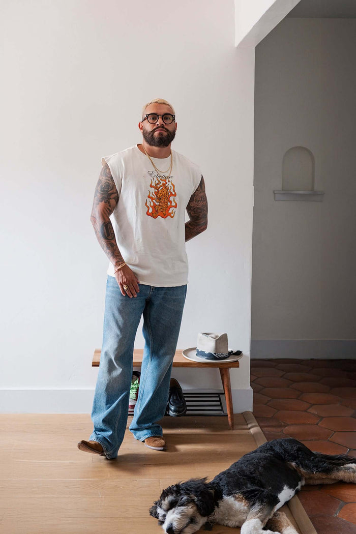 Man wearing a Jaguar Graphic T-shirt with flaming artwork, standing indoors next to a sleeping dog.