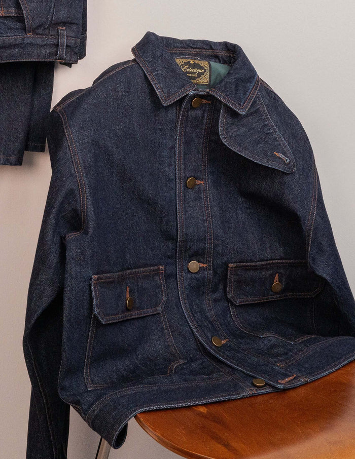 Kura Indigo Jacket featuring cropped structured shape, deep indigo wash, copper stitching, and brass button hardware.