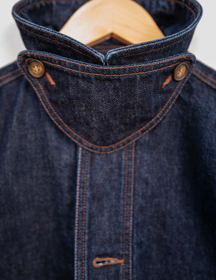 Close-up of the Kura Indigo Jacket showcasing the structured pointed collar and brass button details.