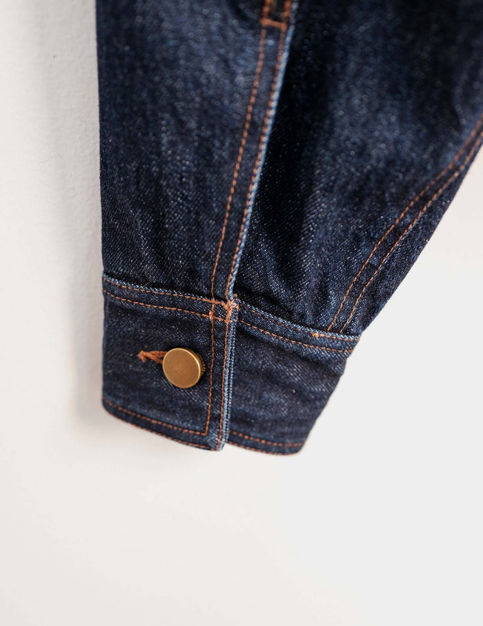 Detail of Japanese denim jacket showing copper button and indigo fabric texture.