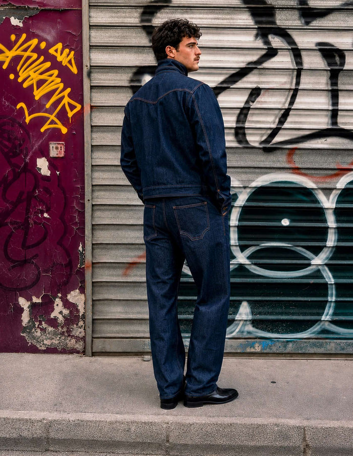 Model wearing Kura Indigo Jeans, showcasing relaxed wide-leg design against urban graffiti backdrop.