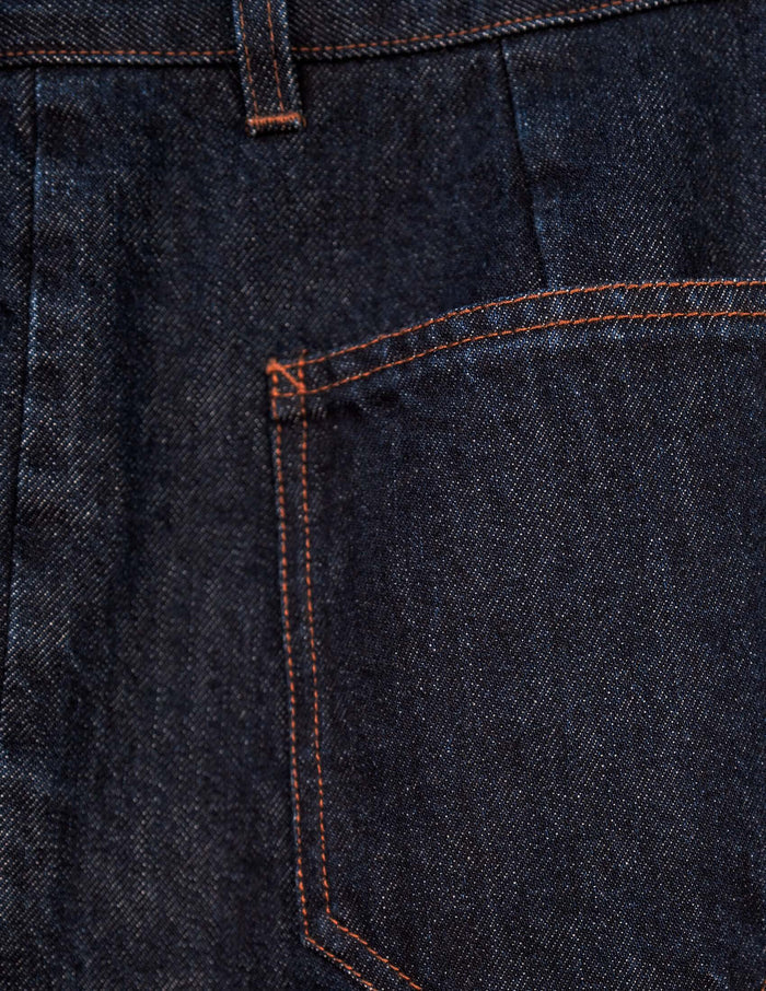 Close-up of the Kura Indigo Jeans showcasing the raw indigo denim, sharp front pleats, and unique angled pockets.