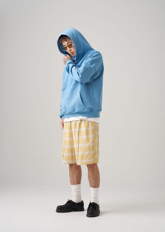 Lightweight terry hoodie in blue worn by a man with yellow plaid shorts and white socks, showcasing relaxed everyday style.