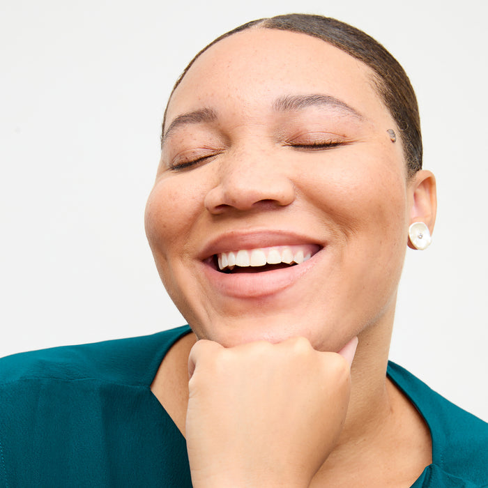 front image of a woman wearing the lillie earrings in pearl