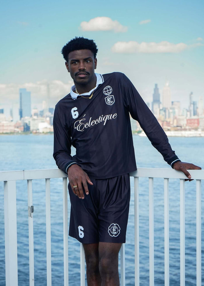 Model wearing a Long Sleeve Soccer Jersey, showcasing sporty style and urban backdrop with city skyline.