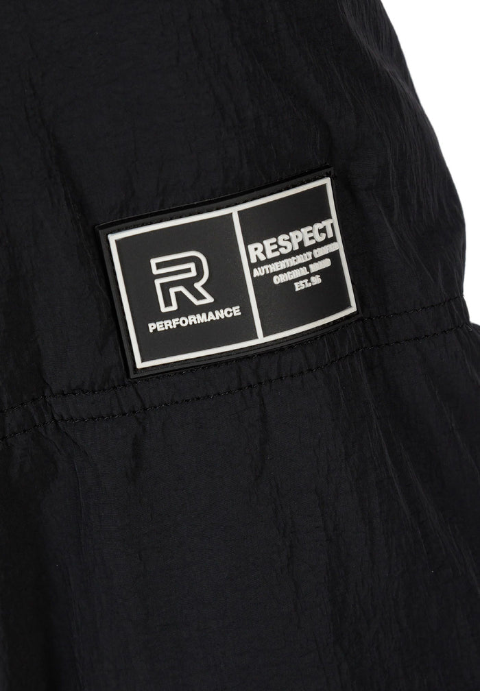 Detail of a black quilted jacket featuring a rubber logo patch.