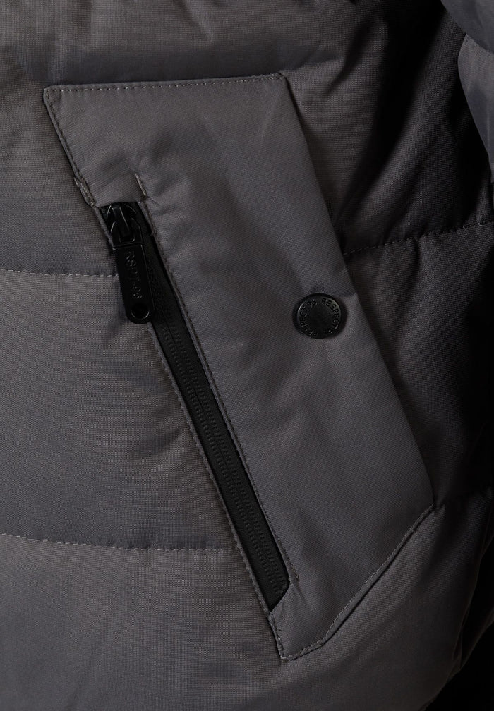 Detail of a grey padded jacket showing a zippered pocket and logo badge.