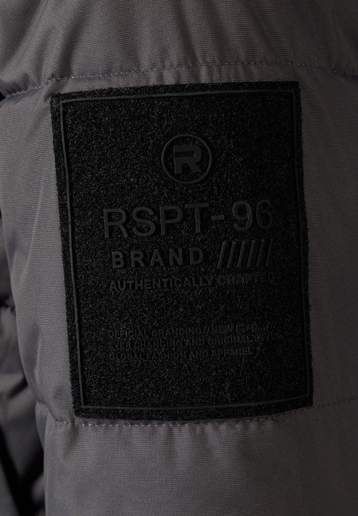 Detail of a grey padded jacket showing a logo badge on the sleeve.