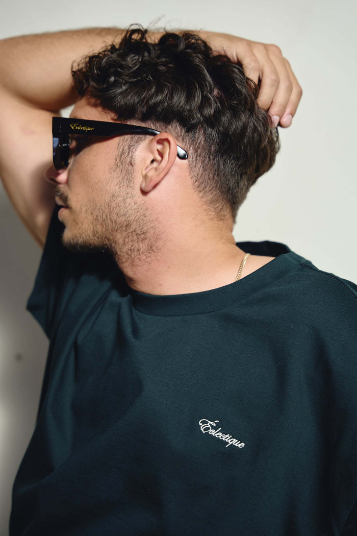 Men's oversized embroidered t-shirt worn by a man with sunglasses, showcasing the embroidered logo on the chest.